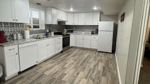 A spacious kitchen with white cabinets, a herringbone-patterned floor, and a microwave.