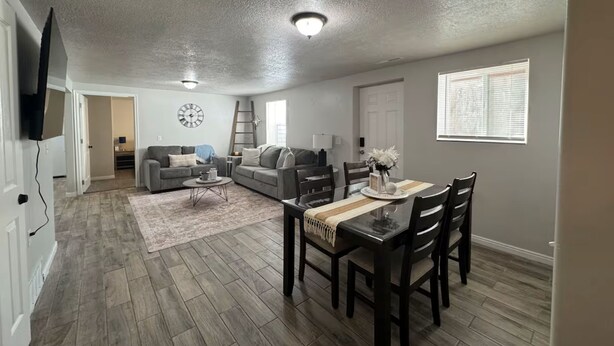 A spacious living room with a dining area, a fireplace, and a large window.