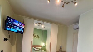 A bedroom with a bed, a TV mounted on the wall, a wardrobe, and a mirror. - Mazzini28, A1 Caserta North, Royal Palace, concerts, Naples, coast, southern Italy (Casapulla)