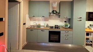 A compact kitchen with a central island, a built-in oven, and a ceiling light fixture. - Mazzini28, A1 Caserta North, Royal Palace, concerts, Naples, coast, southern Italy (Casapulla)