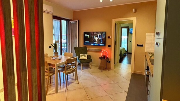 A modern living room with a TV, dining area, and kitchen. - Mazzini28, A1 Caserta North, Royal Palace, concerts, Naples, coast, southern Italy (Casapulla)