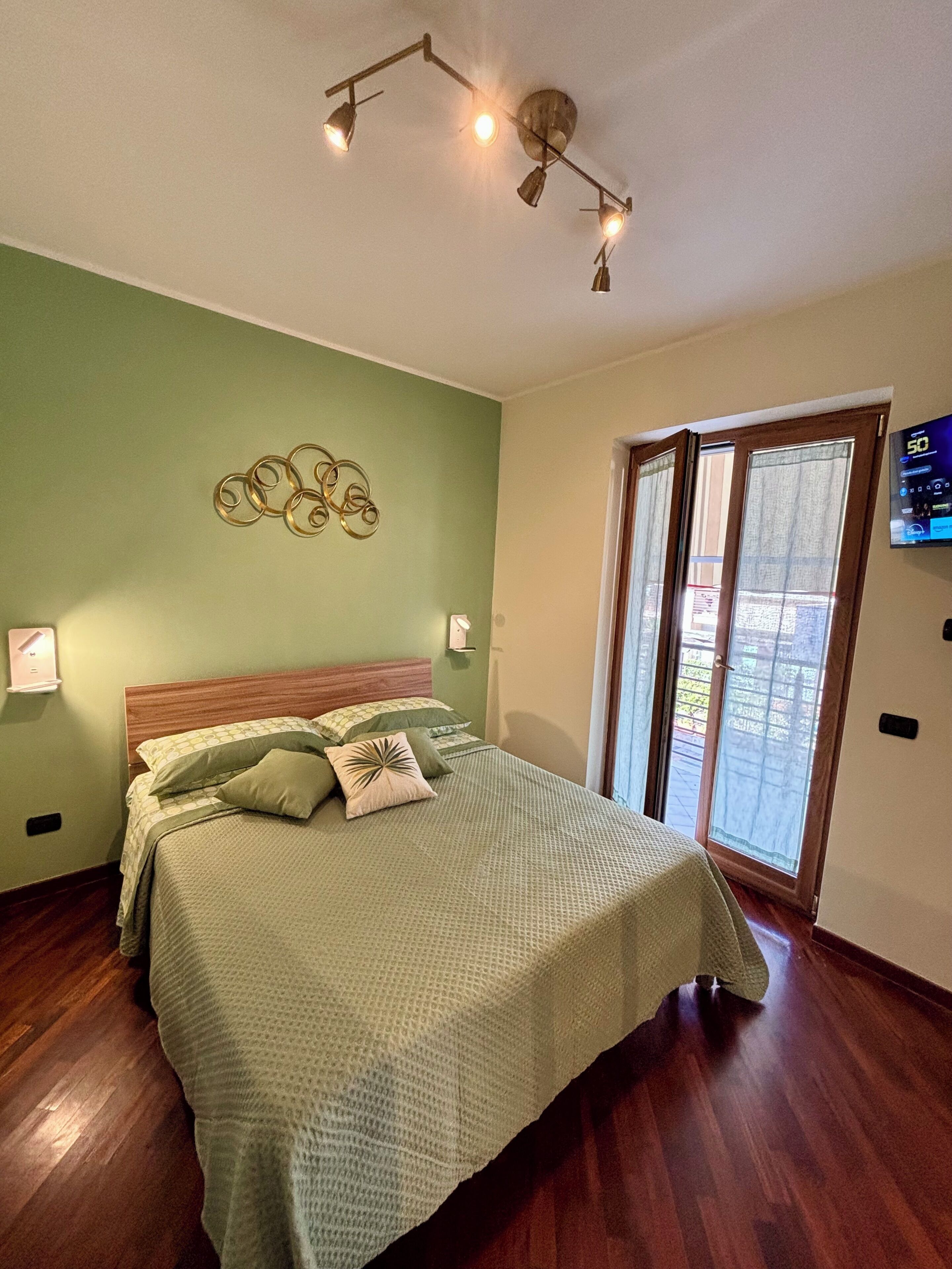 Een slaapkamer met een bed, een wandlamp en een raam met gordijnen.