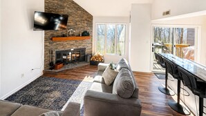 Un salon moderne avec une cheminée en pierre, un téléviseur à écran plat, un canapé et un coin bar.