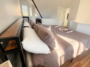 Un dormitorio con una cama en literas, una mesita y un ventanal.