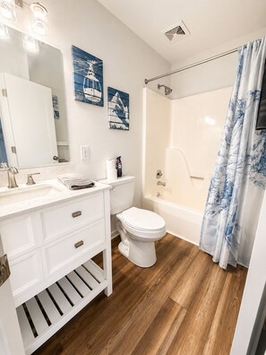 Ein Badezimmer mit weißem Waschtisch, Toilette, Badewanne und Duschvorhang.