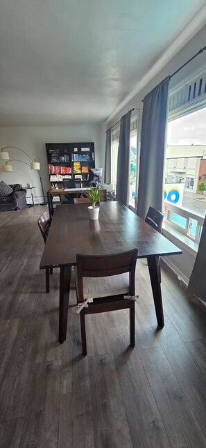 Una habitación amplia con una gran mesa de comedor, sillas, una estantería y una planta en maceta.