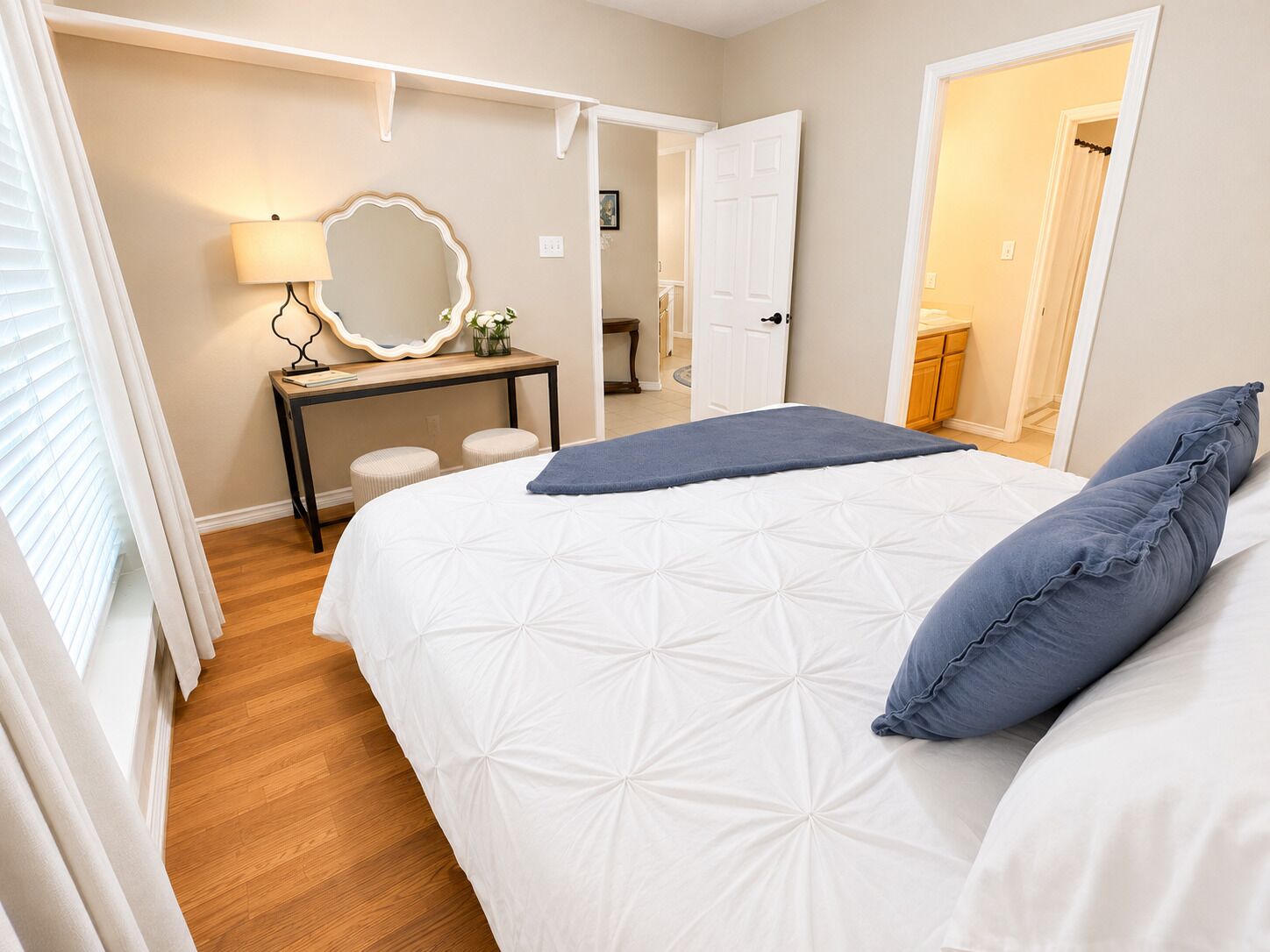 Une chambre à coucher comprenant un lit, une table de chevet, un miroir et une porte donnant sur une autre pièce.