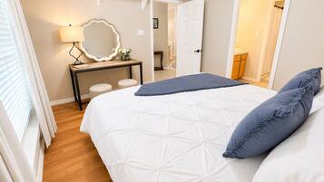 Une chambre à coucher comprenant un lit, une table de chevet, un miroir et une porte donnant sur une autre pièce.