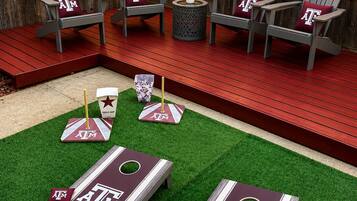 Un jardin avec une terrasse en bois, un espace salon extérieur et un mini-parcours de golf.