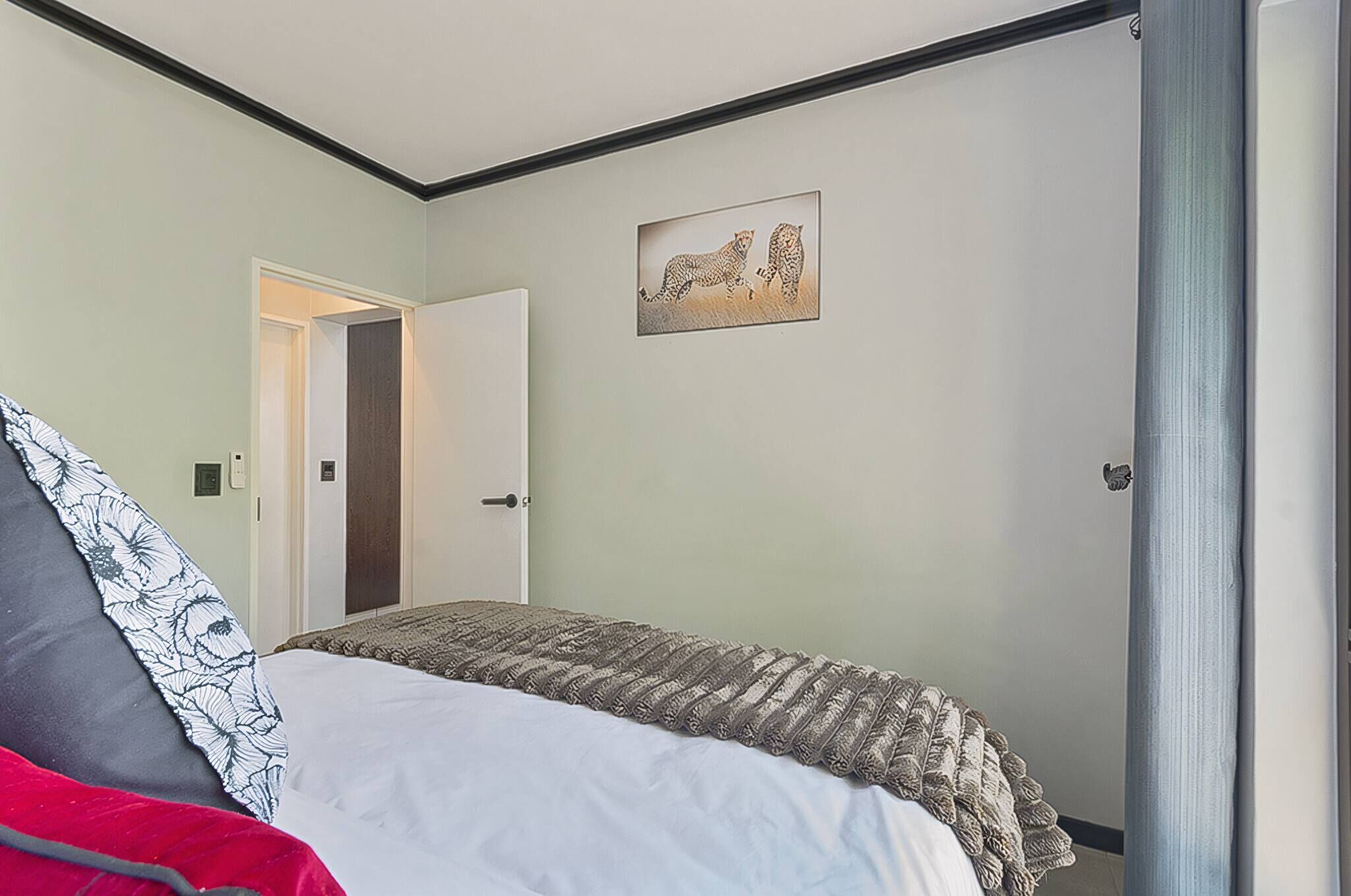 Un dormitorio con cama, una puerta y un cuadro colgado en la pared.