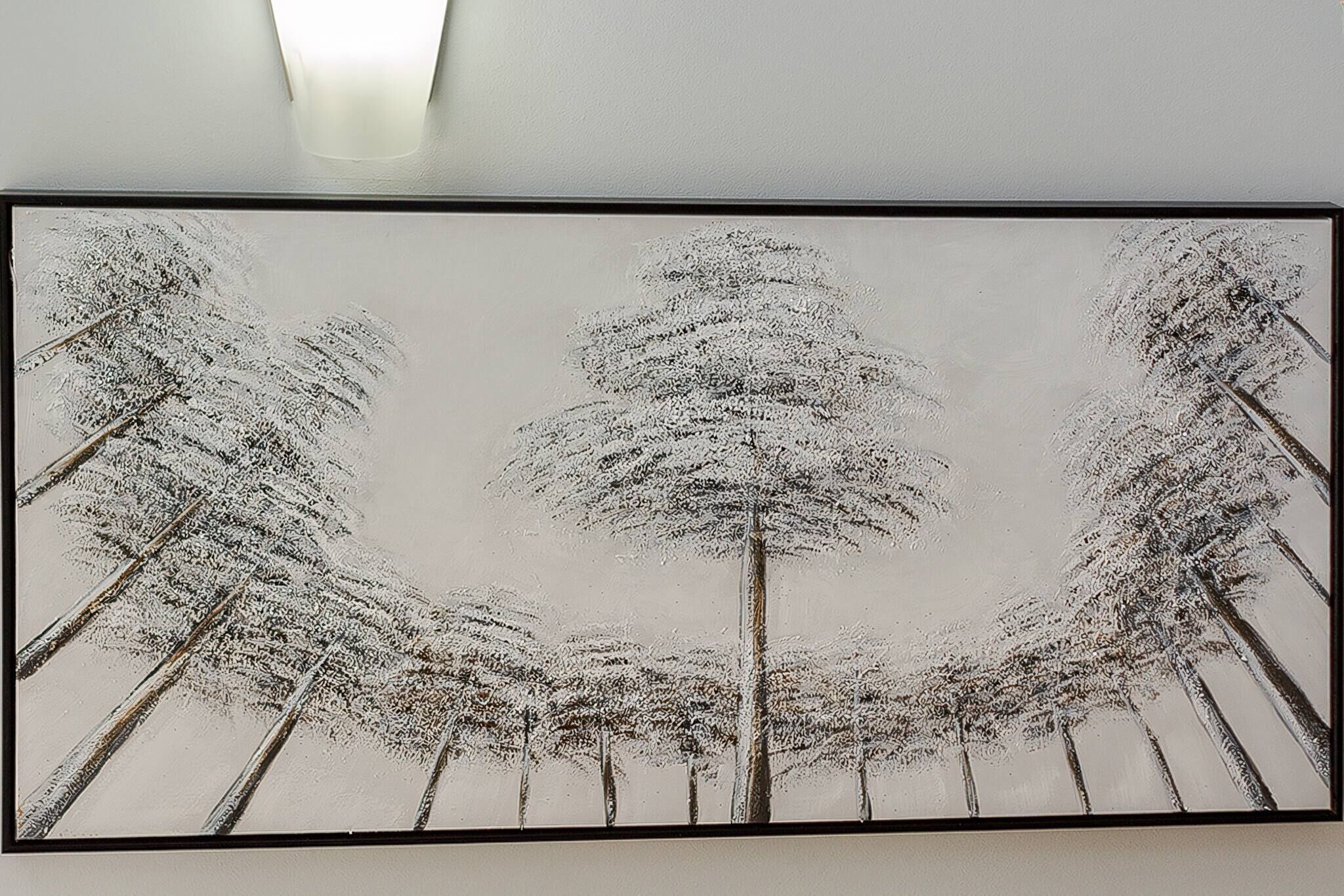 A framed artwork of a snowy landscape with trees.