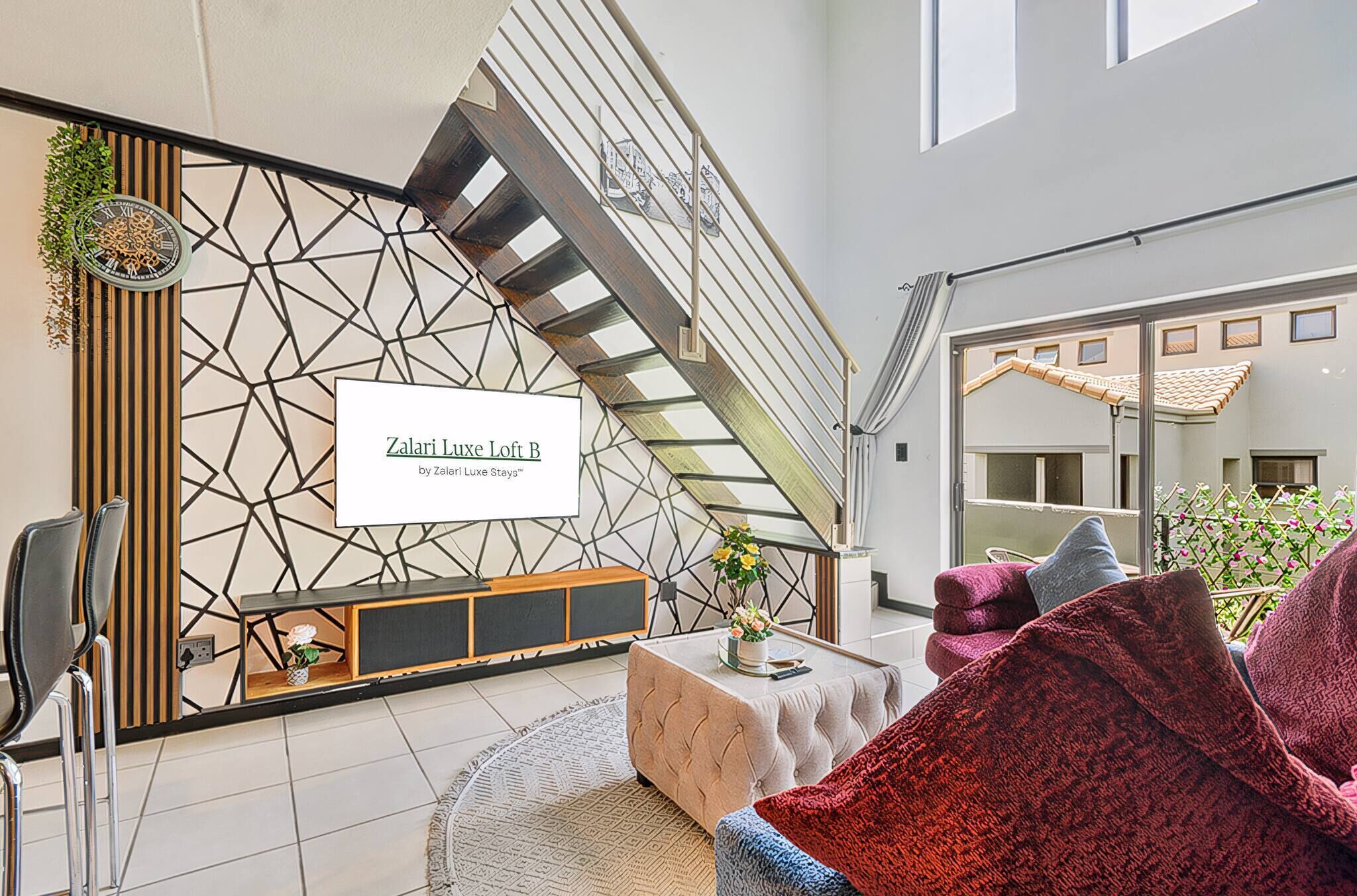Een modern interieur met een geometrisch wandontwerp, een trap, een bank en een salontafel.