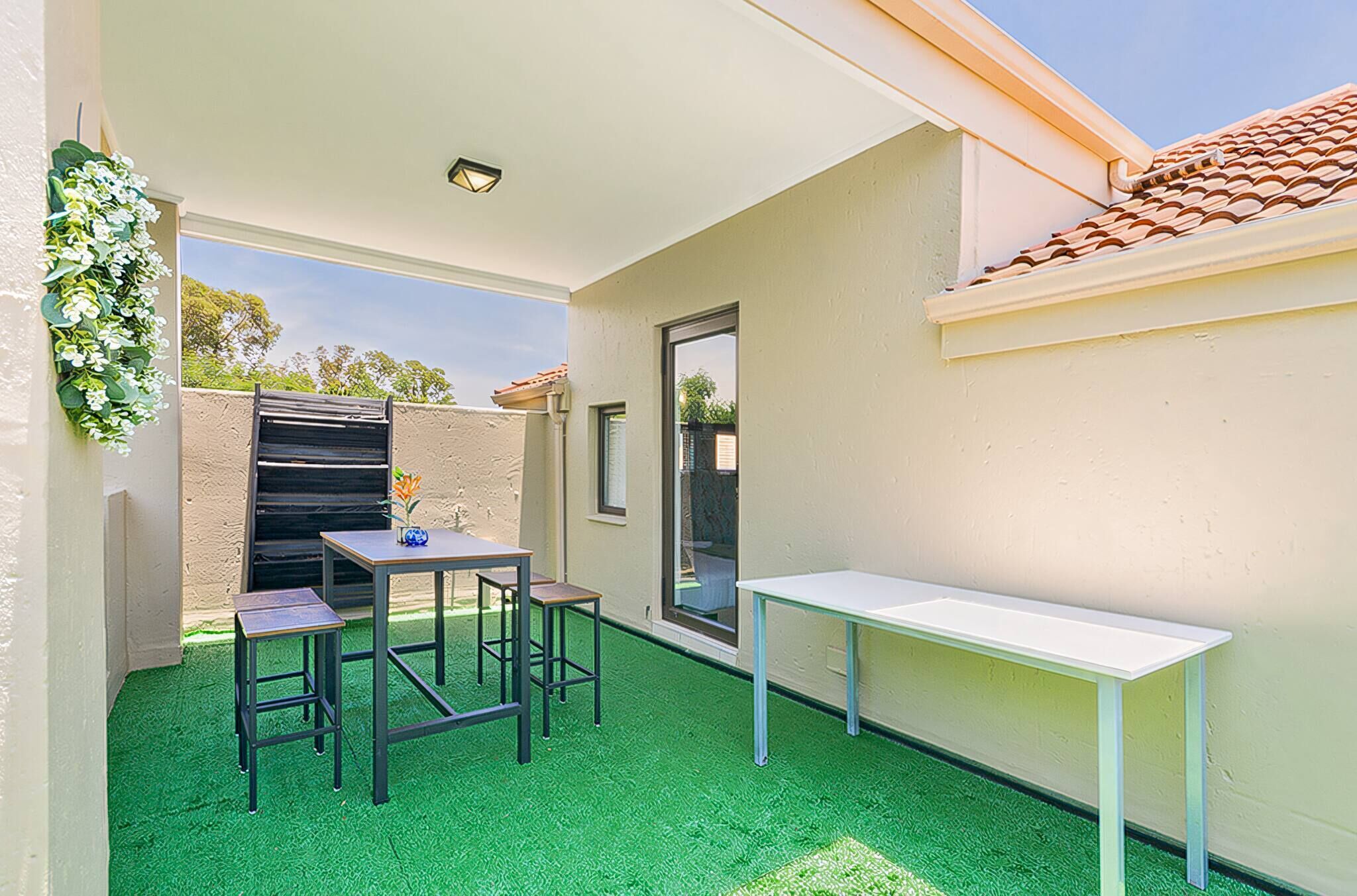 A patio with a table and chairs, a bench, and a wall-mounted planter.