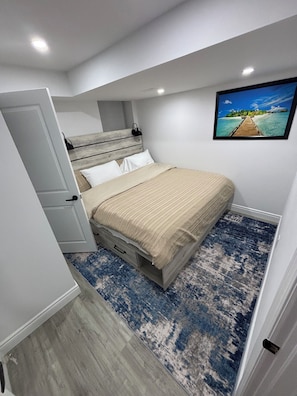 Une chambre à coucher avec un lit, une table de chevet, une commode, un tableau et un plancher en bois.
