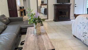 A living room with a sofa, a coffee table with a vase of flowers, a fireplace, a television, and a door.