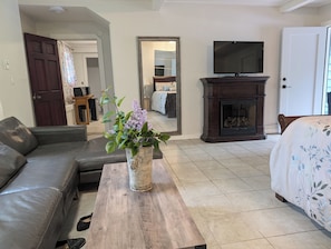 A living room with a sofa, a coffee table with a vase of flowers, a fireplace, a television, and a door.