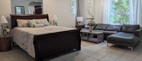 A bedroom with a bed, bedside tables, a sofa, and a window with curtains.