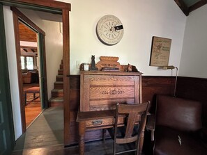 A wooden desk with a globe, a framed picture, and a lamp. A chair is in front of the desk.