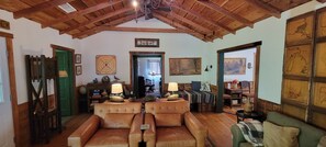 A cozy room with a high wooden ceiling, a green door, a fireplace, and a bed with a view.