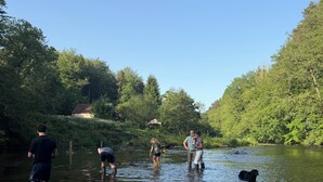 Un gruppo di persone che si inoltra in un fiume, circondato dal verde.