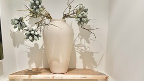 Un bagno con il water, un lavandino e un vaso con fiori secchi su uno scaffale.