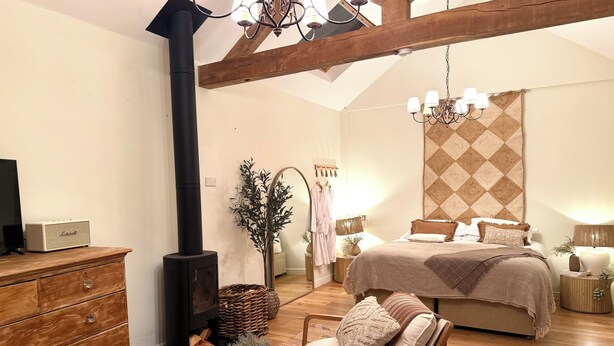 Una camera da letto con un letto grande, un comò in legno, una stufa nera, un lampadario e uno specchio.