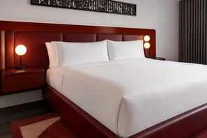 Ein Hotelzimmer mit einem großen Bett, zwei Nachttischen und einem an der Wand befestigten Kunstwerk.