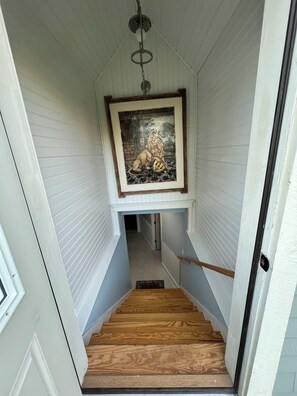 Una escalera con una obra enmarcada encima, que lleva a una puerta.