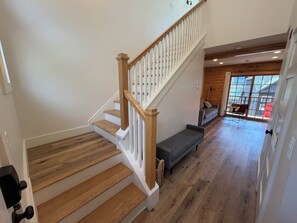 A staircase with wooden steps and white railings, a bench, and a view of a wooden interior through a glass door. - Deluxe Lodge Lakefront On Lake George #2 (Lake George)