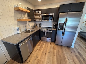 A modern kitchen with a dishwasher, oven, microwave, and refrigerator. - Deluxe Lodge Lakefront On Lake George #2 (Lake George)