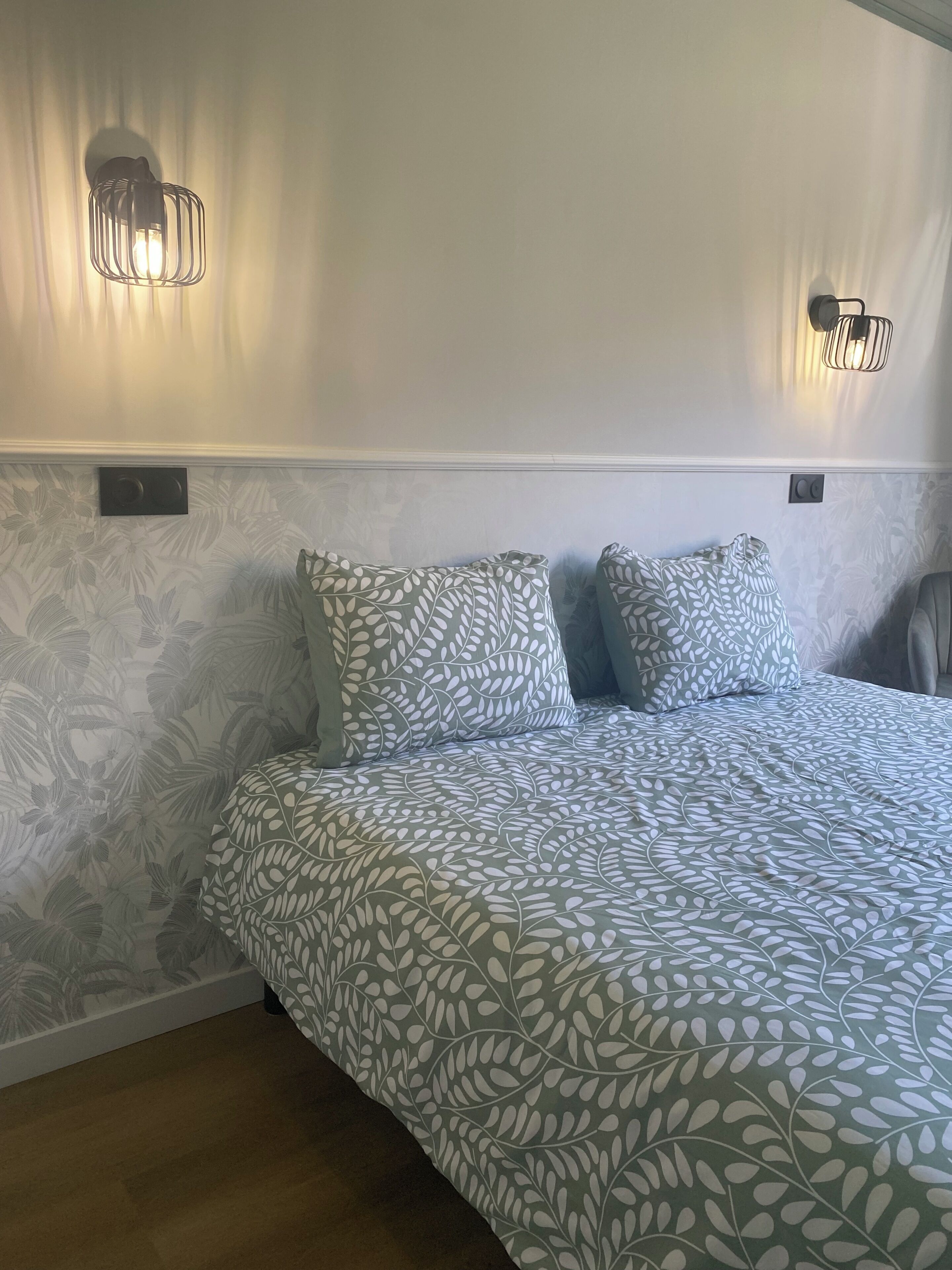 Een slaapkamer met een bed, een behangen muur en twee wandlampen.
