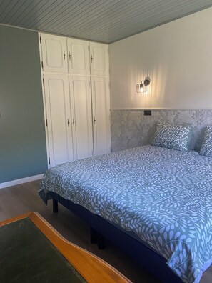 Un dormitorio con cama, armario, lámpara de pared y pared con diseño.