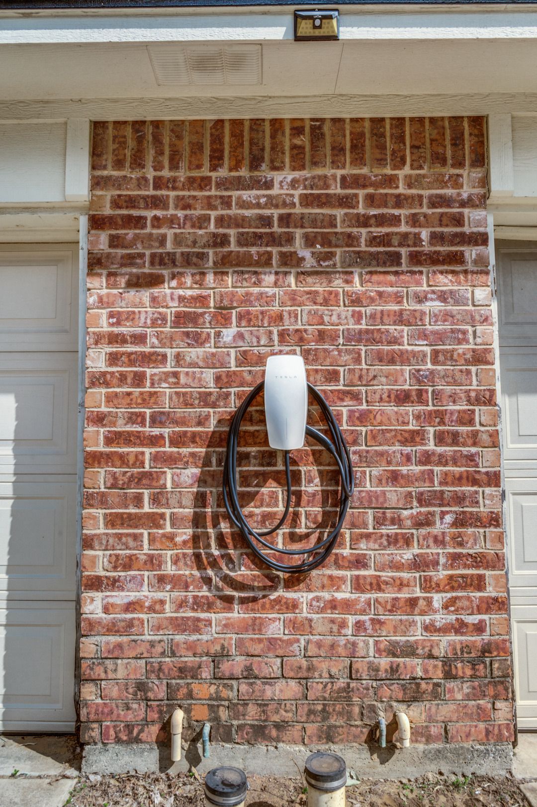 Eine Ziegelwand mit einer Tesla Ladestation.