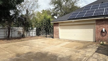 Een woongarage met een witte garagedeur, zonnepanelen op het dak en een gevel van baksteen.