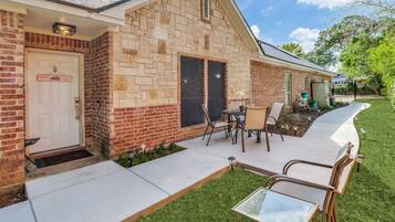 A brick building with a door labeled 'AMERICA'S BEST,' a patio with outdoor furniture, and a well-maintained lawn.