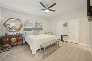 A bedroom with a bed, dresser, mirror, ceiling fan, and two doors. - Walk to AT&T Stadium Modern Arlington Oasis Sleeps 8 (Arlington)