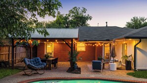 Um quintal com piscina, móveis de jardim e luzes de fada.