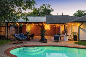 A backyard with a swimming pool, patio furniture, and string lights. - Designer Pool Retreat (Houston)