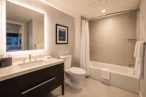 Un baño moderno con un espejo grande, lavamanos dobles, inodoro y bañera.