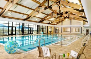 Una piscina interior con techo alto y amplias ventanas.
