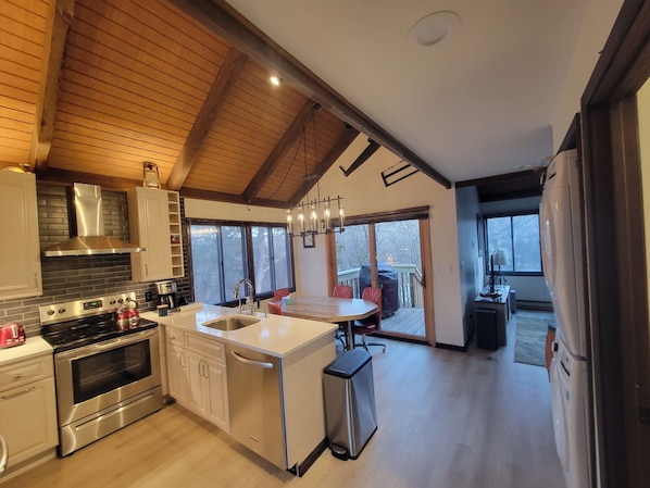 Una cocina moderna con una isla central, electrodomésticos de acero inoxidable y una zona de comedor con vistas.