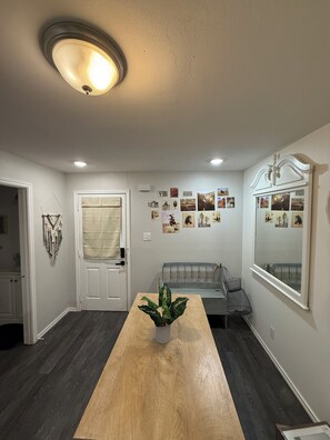Ein Zimmer mit Holztisch, Blumentopf, Bank und einer mit Bildern verzierten Wand.