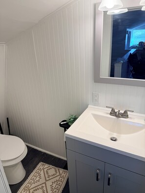 Un baño con un lavabo blanco, un espejo y un inodoro.