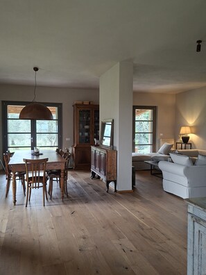 A spacious room with a wooden dining table, chairs, a sofa, and a cabinet. - Il Poggio Luxury villa in Tuscany (Toscana)