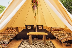 A tent with two beds, a bench, and a hanging decoration. - Olive Ranch luxury bell tent glamping (Alfriston)