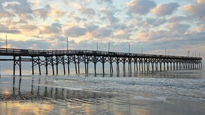 Un muelle se adentra en aguas tranquilas bajo un cielo nublado.