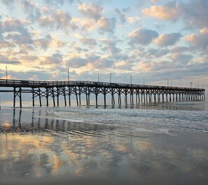 Eine Pier, die sich in ruhiges Wasser erstreckt, mit bewölktem Himmel darüber.
