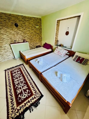 Ein Zimmer mit zwei Betten, einer Steinwand, einem Spiegel und einem gemusterten Teppich.