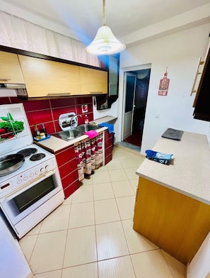 A compact kitchen with a stove, sink, and a small refrigerator.
