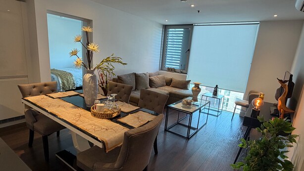 Uma sala de estar moderna com um sofá, uma mesa de jantar com cadeiras, uma mesa de centro e um vaso decorativo.